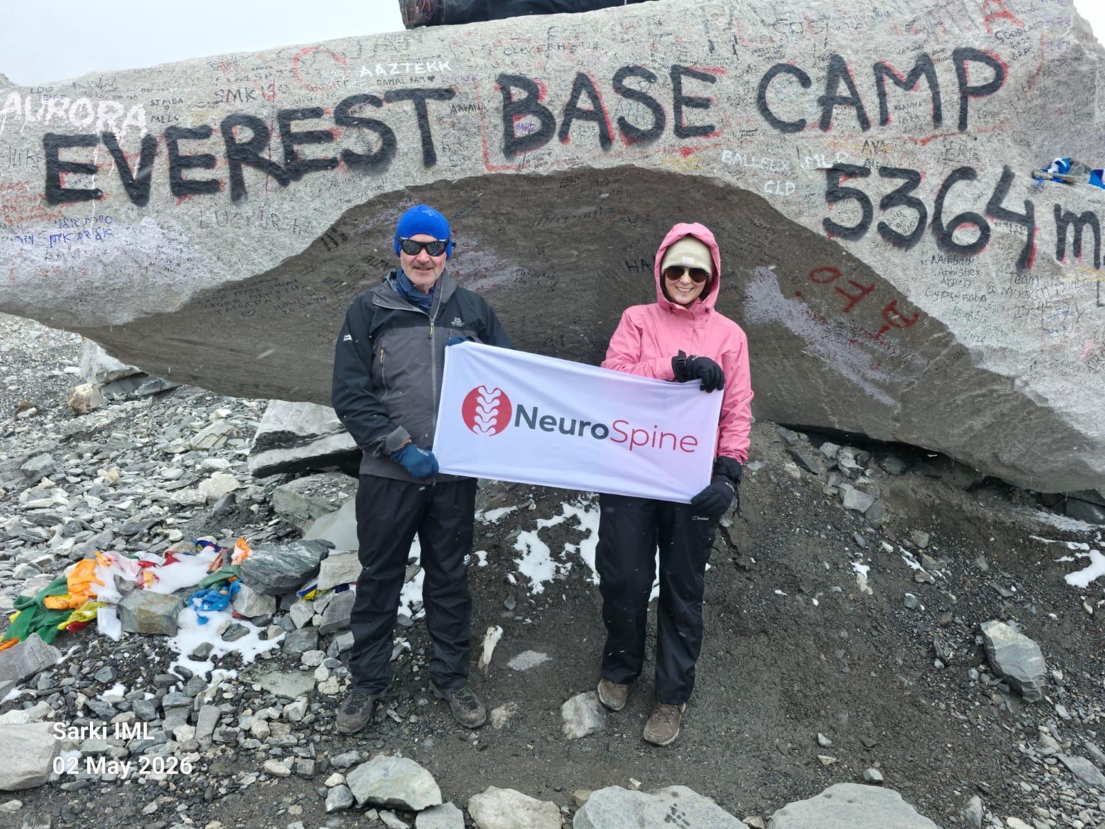 Adrian and Lisa holding a NeuroSpine flag at Everest Base Camp after spine surgery with Michael Kelleher